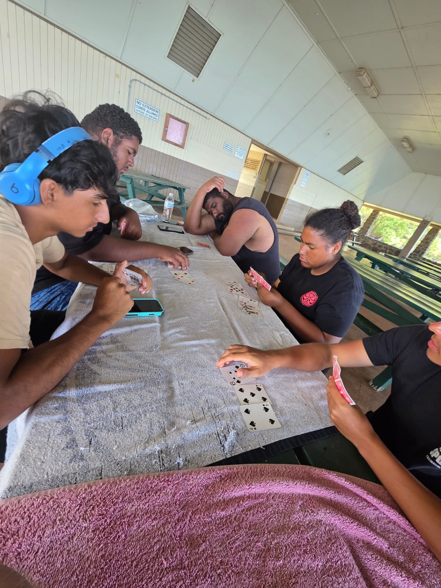 Young people sitting together around a table at a Hawaiʻi Island pavilion