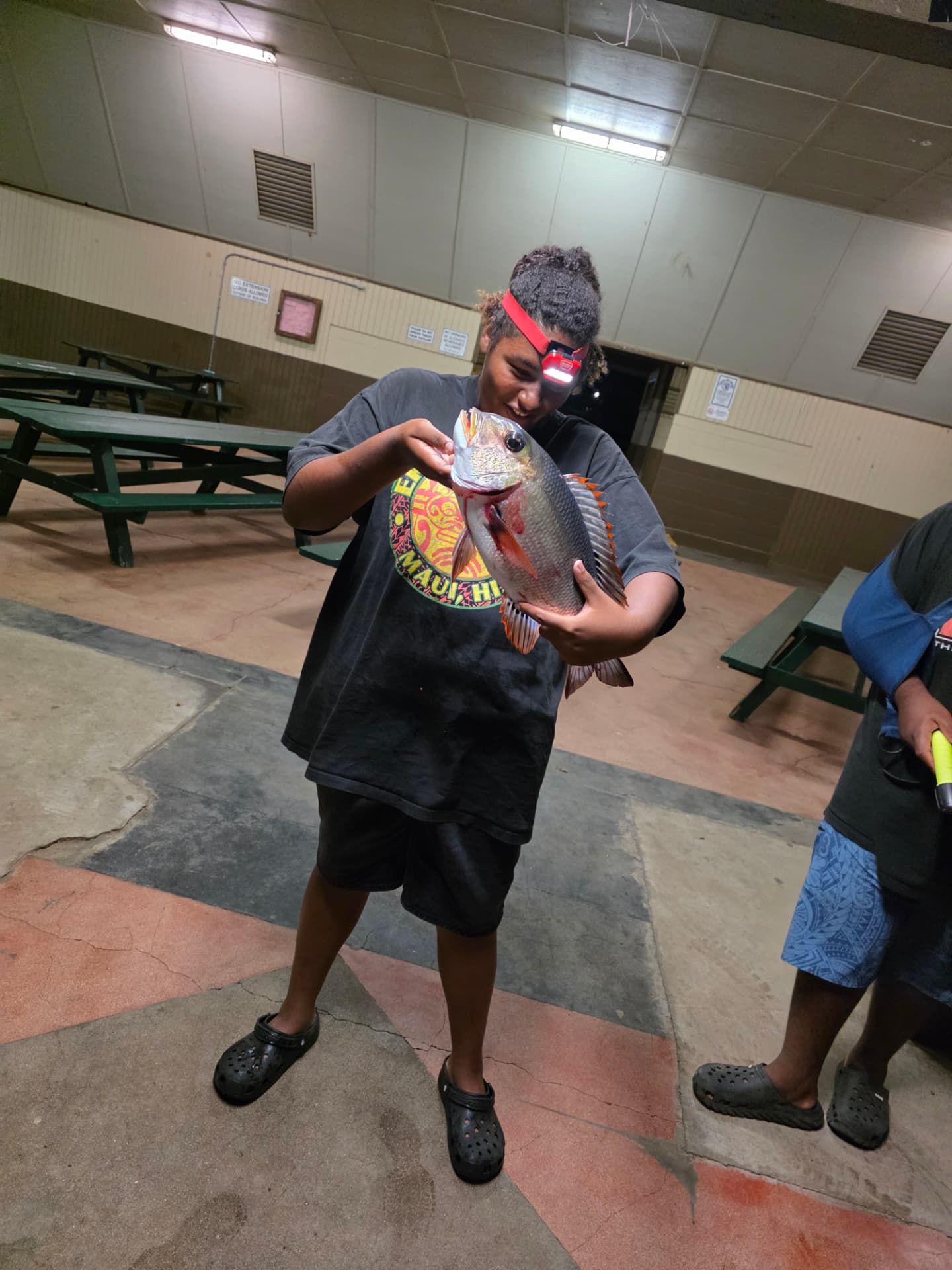A camper proudly holding a fish caught during the youth camping trip