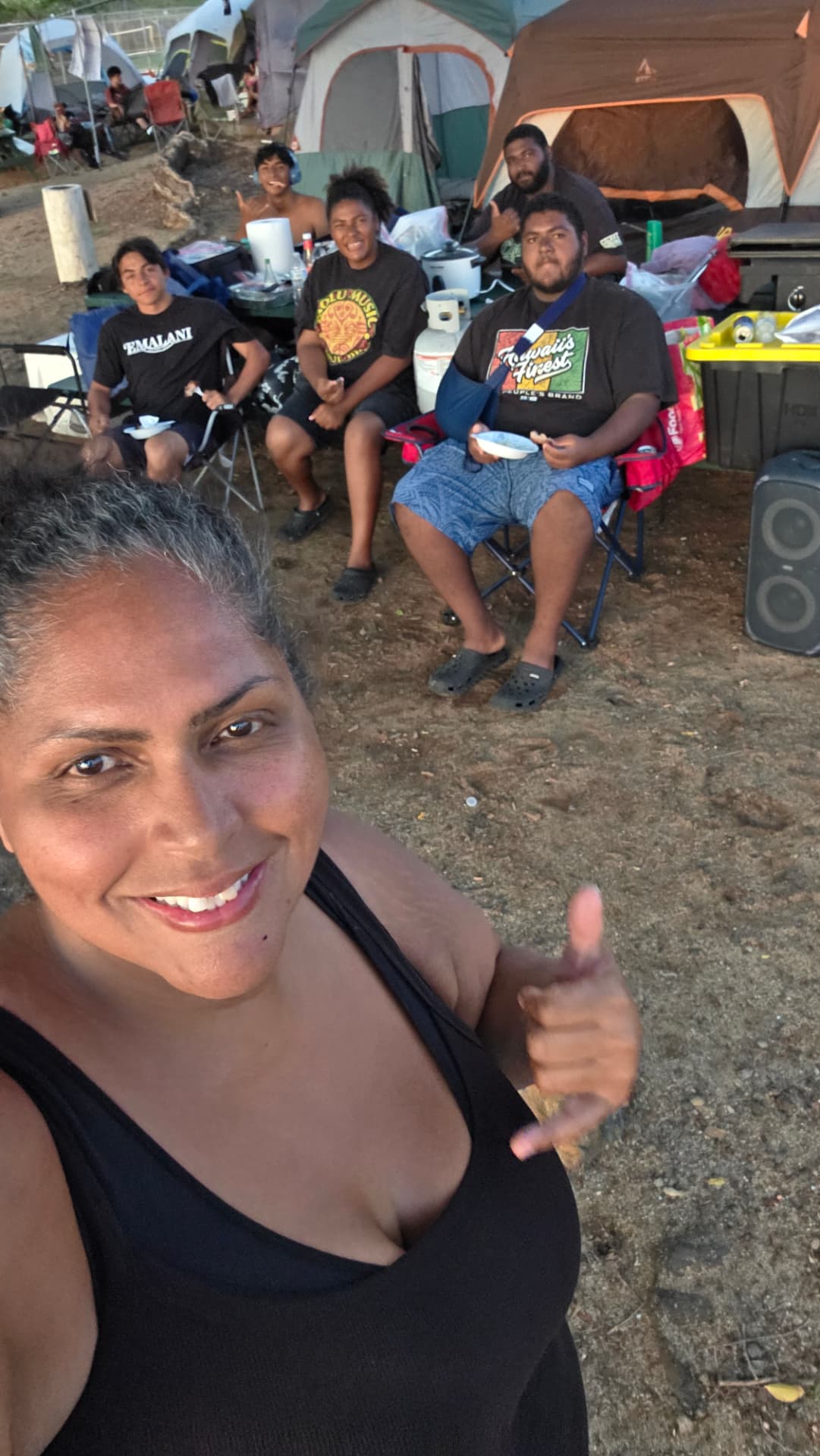 Shaunna Cota with youth gathered around camp chairs sharing a meal